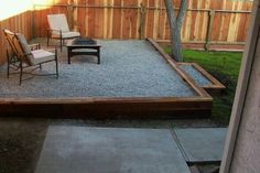 an outdoor patio with chairs and gravel in the foreground, next to a wooden fence