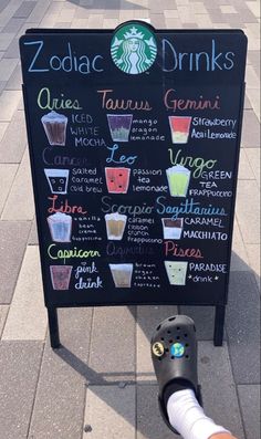 a menu board with drinks on it and a person's foot resting next to it