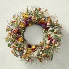 a wreath with dried flowers and leaves hanging on the wall