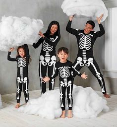 a family dressed in skeleton costumes posing for a photo with clouds and clouds behind them