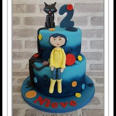 a blue cake with a girl and a cat on top that says 2 in the middle