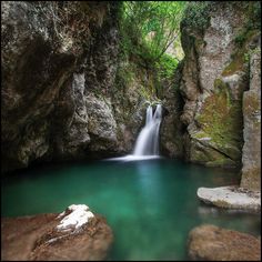 there is a waterfall in the middle of some rocks with water running down it's sides