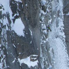 a man climbing up the side of a snow covered mountain