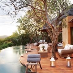 an outdoor deck with chairs and lamps next to a pool