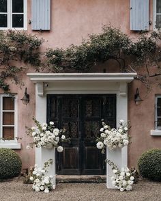 a couple of white flowers sitting in front of a black door with blue shutters