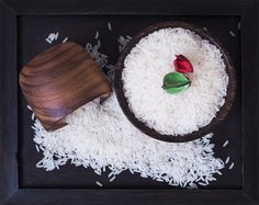 white rice in a wooden bowl with a red rose on top