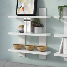 two white shelves with books and bowls on them in a room next to a couch