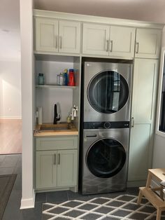 a washer and dryer in a small room with white cabinets on the wall