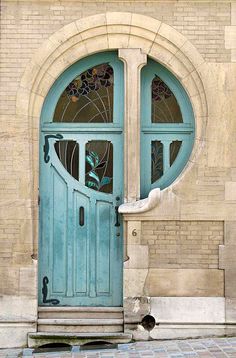 a green door on the side of a brick building with arched glass and stone steps