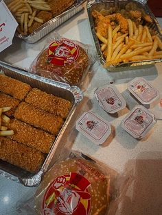 several trays of chicken strips, french fries and other foods on a counter top