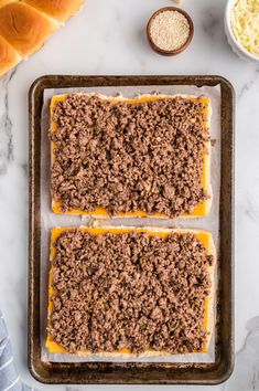 three square pieces of bread with cheese and ground beef on top, sitting on a baking sheet