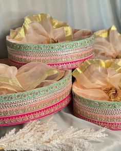 three baskets with gold and pink ribbons in them