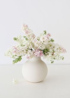 a white vase with pink and white flowers in it