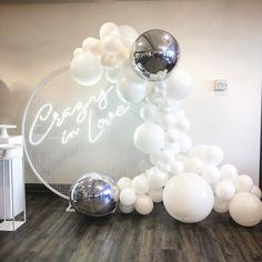 white balloons and silver balls are on the floor next to a sign that reads prop'd up