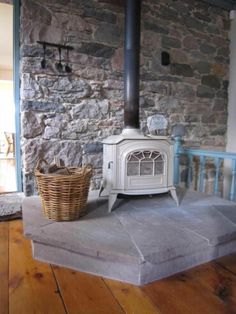 a wood burning stove sitting on top of a hard wood floor next to a basket