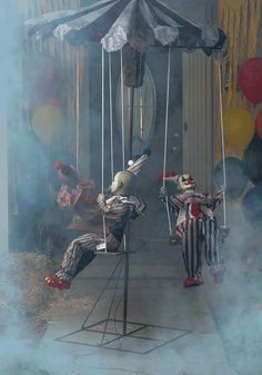 two clowns sitting on swings in front of a building