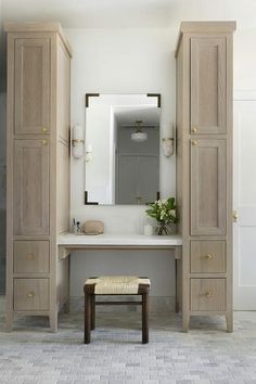 a white bathroom with wooden cabinets and a bench in front of the mirror on the wall