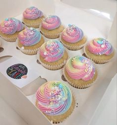 cupcakes with rainbow frosting and sprinkles in a white box