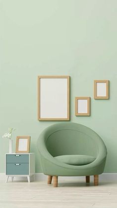 an empty room with some frames on the wall and a green chair in front of it