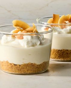 two desserts in small glass dishes on a table with fruit and whipped cream topping