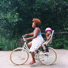 a woman and her child are riding on a bicycle