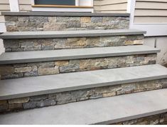 a set of stone steps leading up to a front door on a home's porch