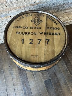 a barrel sitting on top of a wooden floor next to a brick wall with writing on it