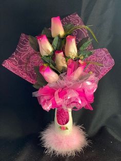 a vase filled with pink roses and feathers