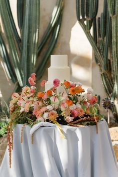 a wedding cake sitting on top of a table covered in white cloths and flowers