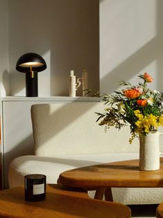 a vase filled with flowers sitting on top of a wooden table next to a white couch