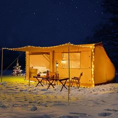 a tent is set up in the snow at night with lights strung from it's roof