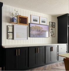 a kitchen with black cabinets and pictures on the wall