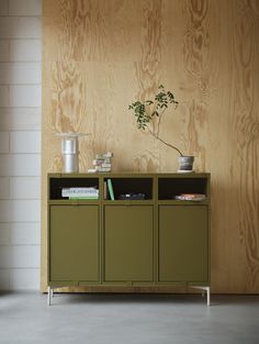 a green cabinet sitting in front of a wall with a plant on top of it