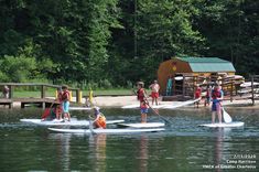 several people on paddle boards paddling in the water near a dock and picnic area