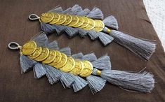 two silver and gold tassels on a brown cloth