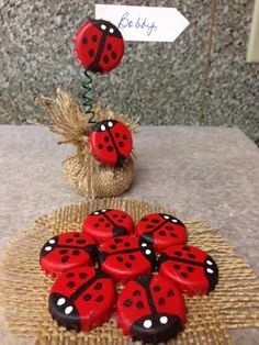 red and black ladybug cookies sitting on top of a table next to a burl