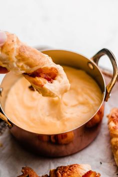 a person dipping some food into a pot