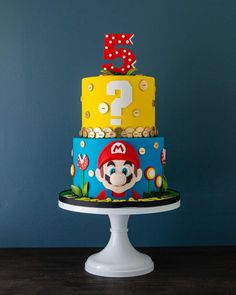 a three tiered cake decorated with mario and the number one on it's top