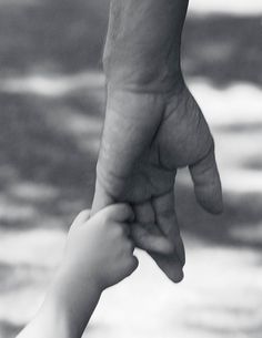 a black and white photo of a person holding the hand of a child's hand