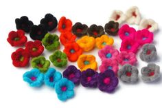 several different colored felt flowers on a white surface