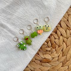 three key chains with small cartoon characters on them sitting on top of a white cloth