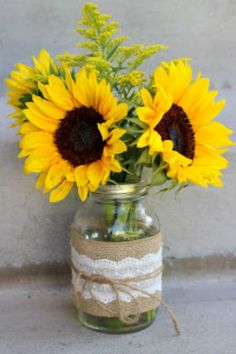 sunflowers are in a mason jar with burlock tied around the top