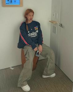 a woman sitting on top of a chair in a room with white walls and wood flooring