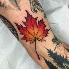 a man's arm with a red and yellow leaf tattoo on the left forearm