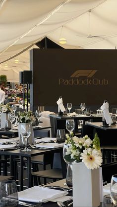 tables and chairs are set up in front of a sign for the paddock club