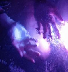 two hands touching each other in front of purple and blue lights on a dark background