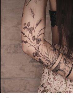 a woman's arm with flowers and leaves tattooed on it