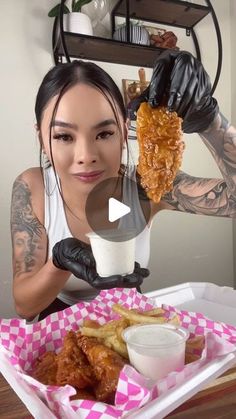 a woman with tattoos holding up a piece of food