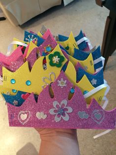 a hand holding a pink and yellow crown with lots of little princess crowns on it