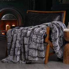 a chair with a blanket on it next to a fire place